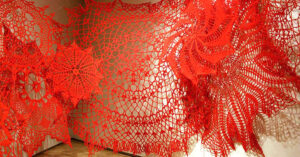 Read more about the article Huge crocheted doilies cover gallery walls like pretty spider webs.