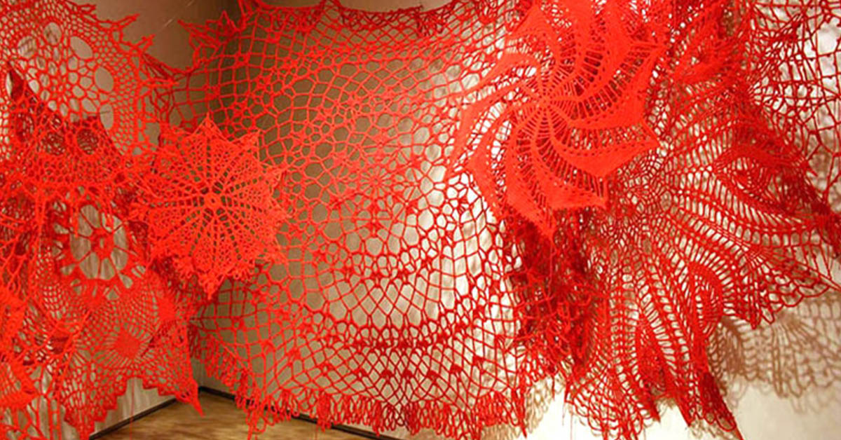 You are currently viewing Huge crocheted doilies cover gallery walls like pretty spider webs.